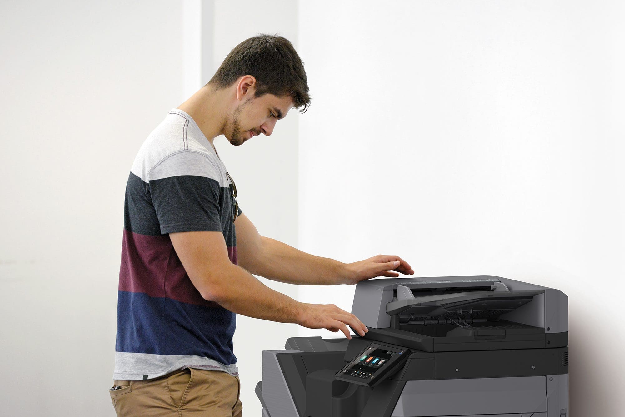 Man standing over a Sharp BP model MFP, utilizing the advanced features for efficient document management, against a white background.