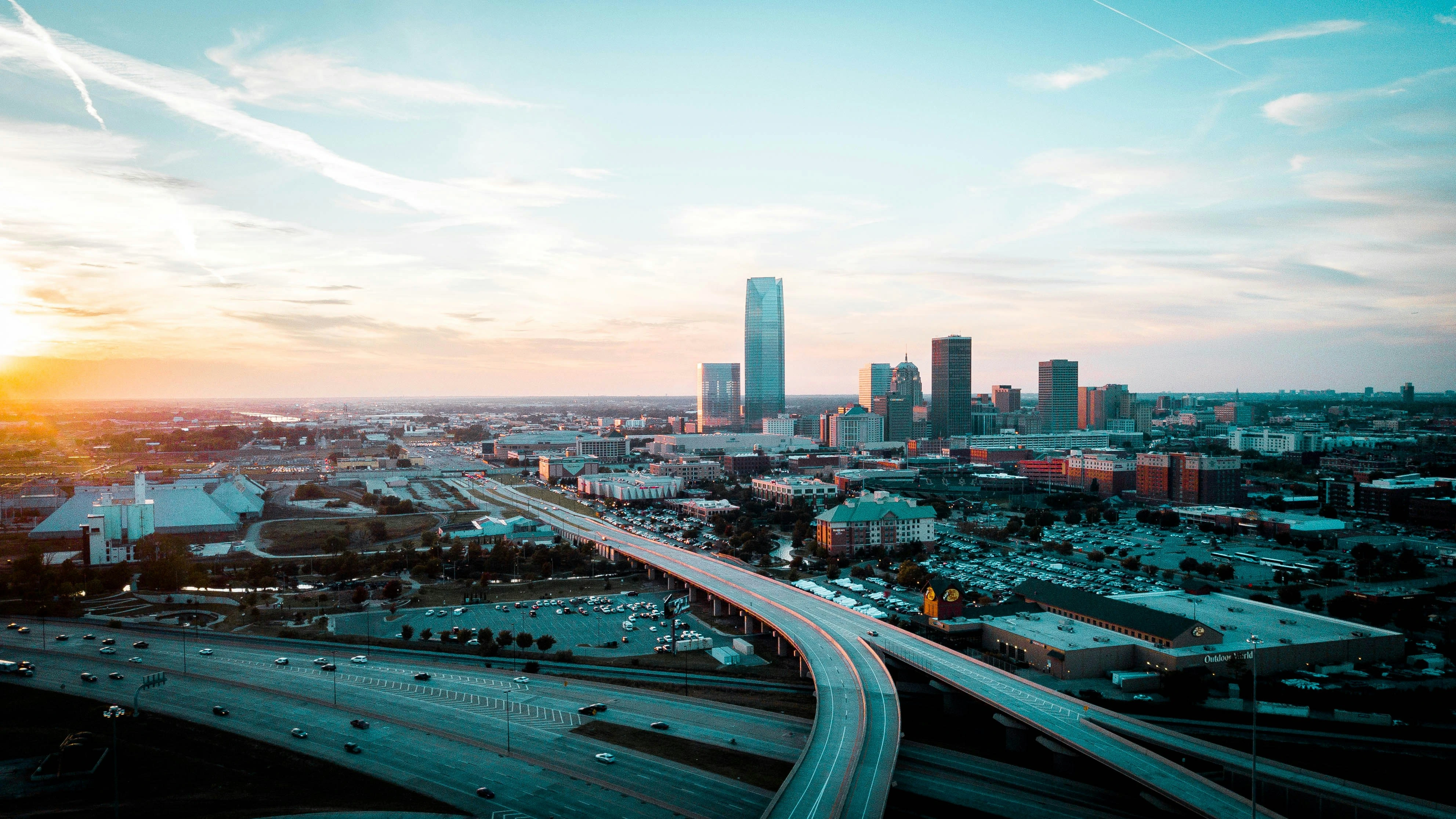 OKC Skyline - OKC's premier Technology Service Provider City skyline at sunset with a curved elevated highway in the foreground and tall glass towers ahead.